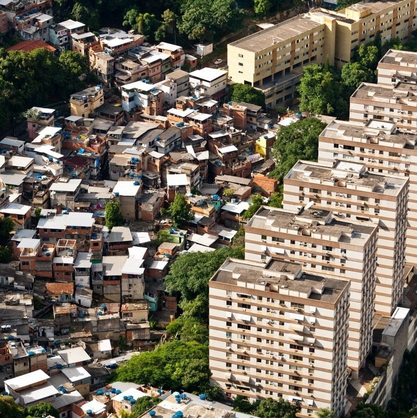 Vista aérea contrastando prédios residenciais modernos e casas aglomeradas em área urbana densa.